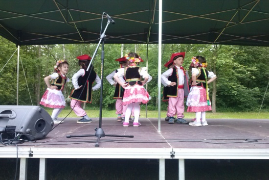 Dzieci w strojach krakowskich tańczą na scenie w Ogrodzie Botanicznym Krakowiaka