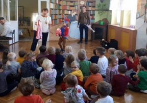 Mężczyzna siedzący przy pianinie, 2 prowadzących oraz 1 przedszkolak z rezkwizytami.