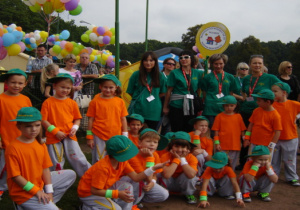 Przedszkolaki oraz pracownicy przedszkola pozują do wspólnego zdjęcia. W tle balony.