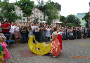 Dzieci przebrane za króla i królową oraz rodzice ogladający przedstawienie.