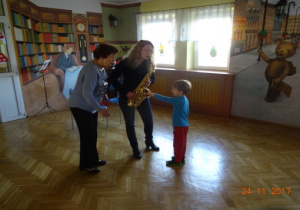 Dwie prowadzące, jedna z nich tzryma instrument, który dotyka chłopiec.