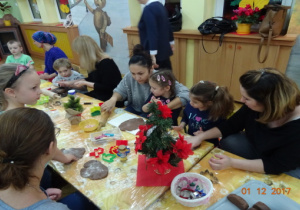 Ozdobione światecznie stoły, przy których dzieci i rodzice wyrabiają ciasto na pierniki.