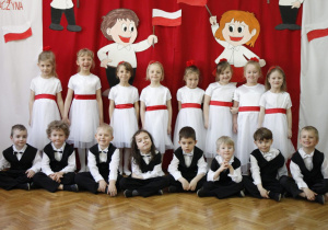 Zdjęcie dzieci z gr. III na tle biało - czerwonej dekoracji.