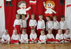 Zdjęcie dzieci z gr. I na tle biało - czerwonej dekoracji.