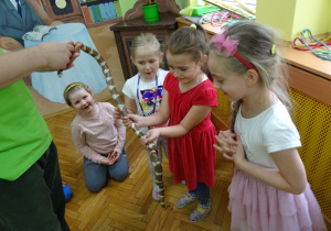 Dziewczynki podziwiają węża. Jedna z nich go trzyma.