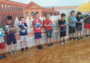 7 chłopców stoi i prezentuje swoje roboty.