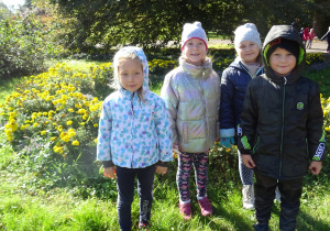 Dzieci stoją przy kwiatach.