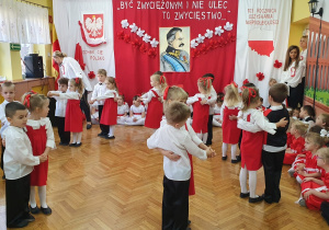 Dzieci wykonują układ taneczny w parach.