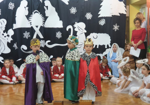 Na środku sceny stoją dzieci odgrywające rolę Trzech Króli.