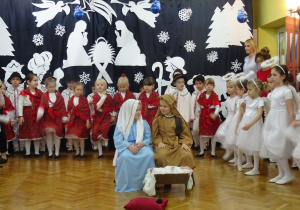 Na środku sceny dzieci odgrywające rolę Józefa, Maryji. Wokól przedszkolaki śpieewają pastorałkę.
