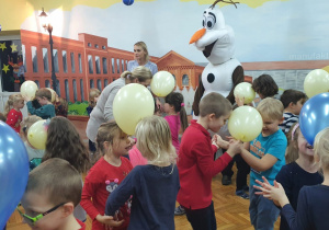 Dzieci z balonami bawią się z bałwankiem Olafem.
