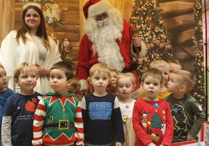 Przedszkolaki na wspólnym zdjęciu z Mikołajem, Śnieżynką i prezentami.