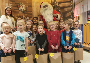 Przedszkolaki na wspólnym zdjęciu z Mikołajem, Śnieżynką i prezentami.