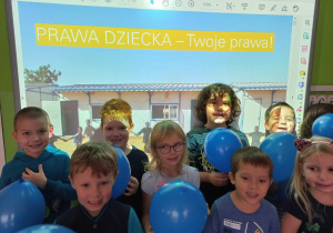 Dzieci z niebieskimi balonami na tle prezentacji "Prawa Dziecka".