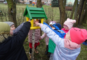 Dzieci wsypują do karmników pożywienie dla ptaków.