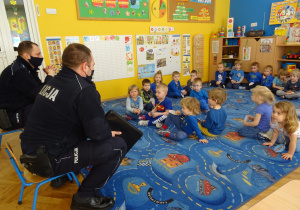 Dzieci słuchają wypowiedzi policjantów.