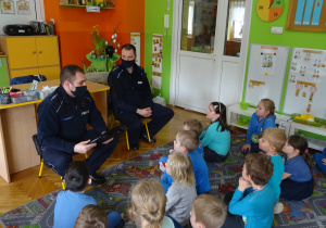 Dzieci słuchają wypowiedzi policjantów.