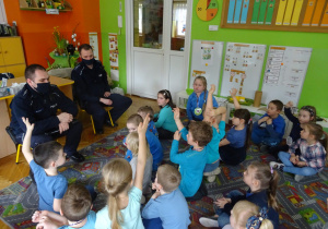Dzieci słuchają wypowiedzi policjantów. Odpowiadają na pytania.