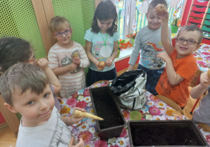 Dzieci przygotowują się do nasadzeń, trzymają w rękach warzywa.