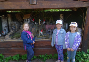 Trzy dziewczynki stoją przed domkami Skrzatów.
