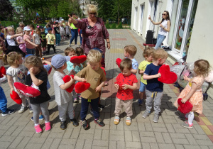 Dzieci bawią się na tarasie, część dzieci trzyma serca.