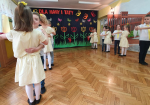 Dzieci w dwóch rzędach tańczą w parach.
