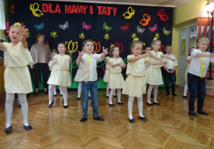 Dzieci w rzędach wykonują uad taneczny.