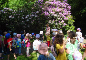 Dzieci z przewodnikiem podziwiają rośliny.