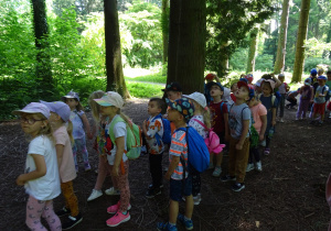 Dzieci spaccerują aleją drzew.