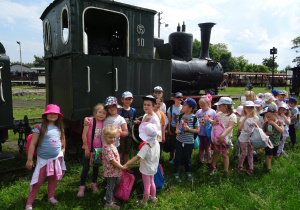 Dzieci stoją przy zabytkowym pociągu.