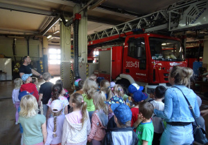 Strażak pokazuje dzieciom wóz strażacki.