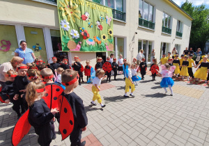 Na scenie znajdują się dzieci w przebraniach biedronek i motyli.