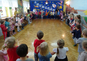 Wszystkie dzieci na tle andrzejkowej dekoracji wykonują układ taneczny.