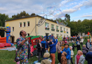 Pokaz baniek mydlanych w ogrodzie przedszkolnym. Wokół dzieci i rodzice.