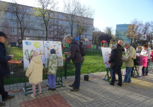 Dziadkowie wraz z wnuczętami malują na sztalugach.