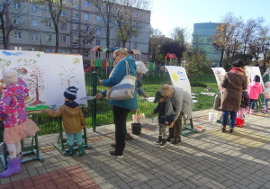 Dziadkowie wraz z wnuczętami malują na sztalugach.