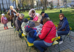 Dziadkowie wraz z wnuczętam robią kasztanowe ludziki.