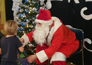 Mikołaj oraz chłopiec otrzymujący prezent.