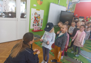 Policjantka pokazuje dzieciom akcesoria policyjne.