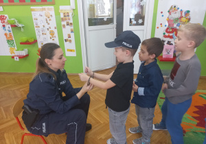 Policjantka pokazuje dzieciom akcesoria policyjne.