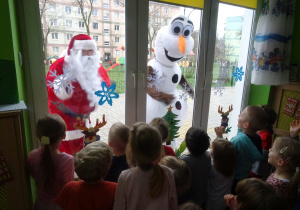 Dzieci podziwiają Mikołaja zza okna.