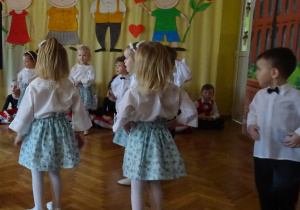 Odświętnie ubrane dzieci tańczą.