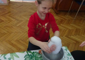Dziewczynka w czerwonej bluzce podczas zabawy z pianą.