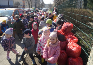 Dzieci i zebrane worki ze śmieciami.