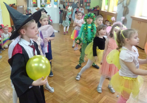 Dzieci w kolorowych strojach, chłopiec trzyma balon.