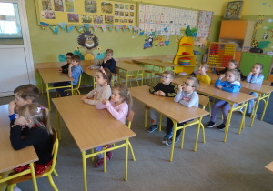 Dzieci siedzą w ławkach.