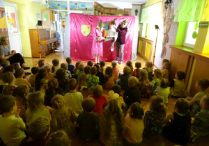 Dzieci oglądają przedstawienie. Dwóch aktorów z pacynką.