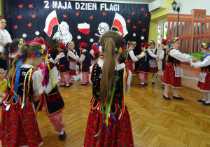 Dzieci tańczą w strojach krakowskich.