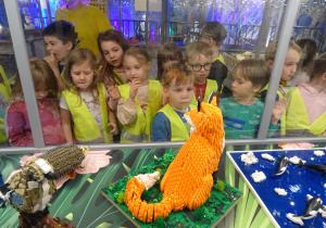 Przedszkolaki oglądają zwierzęta z klocków lego.