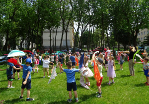 Przedszkolaki machają chustami.
